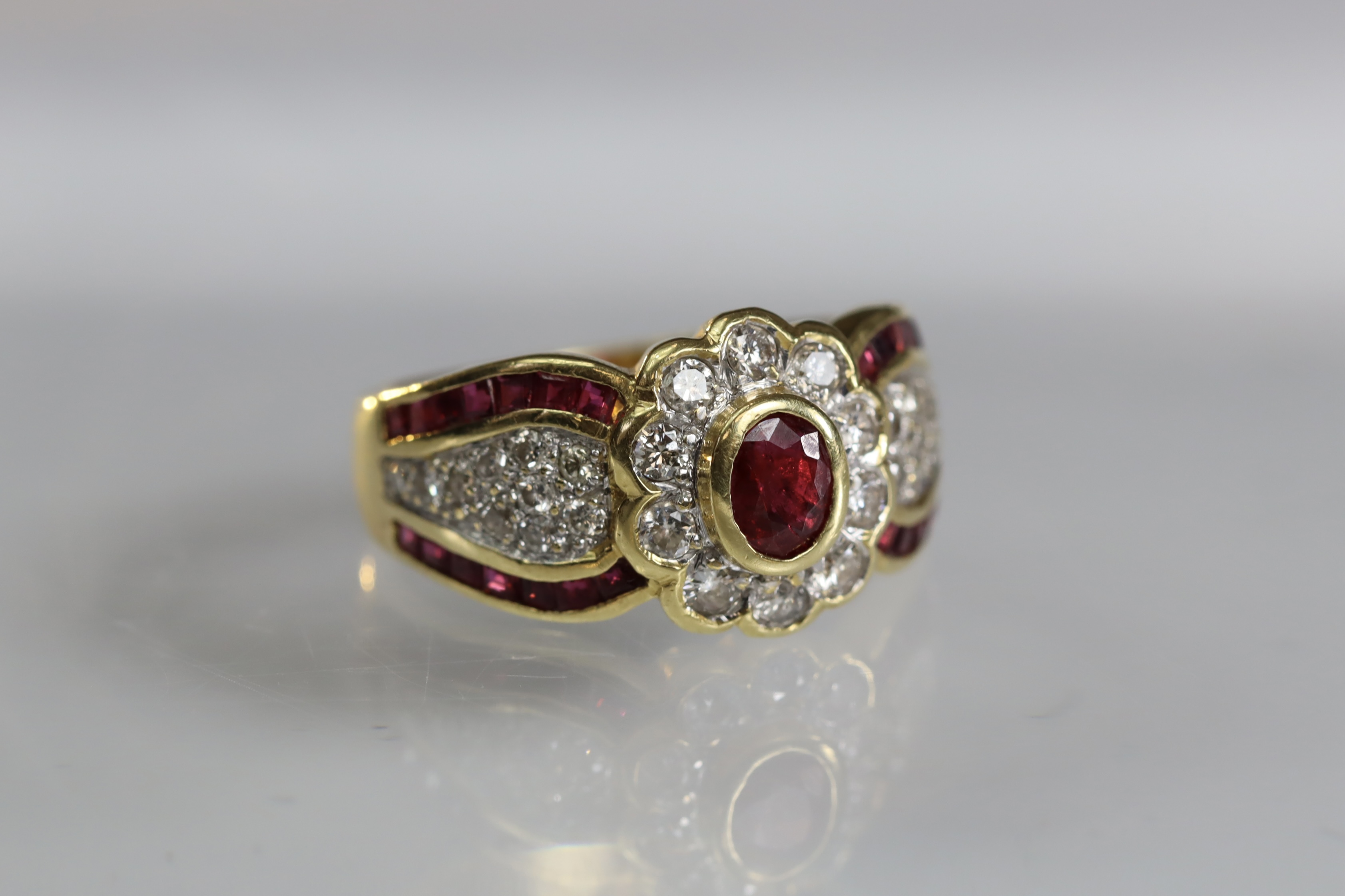 A contemporary 18 carat Yellow Gold, Ruby and Diamond Dress Ring,the oval shaped ruby central