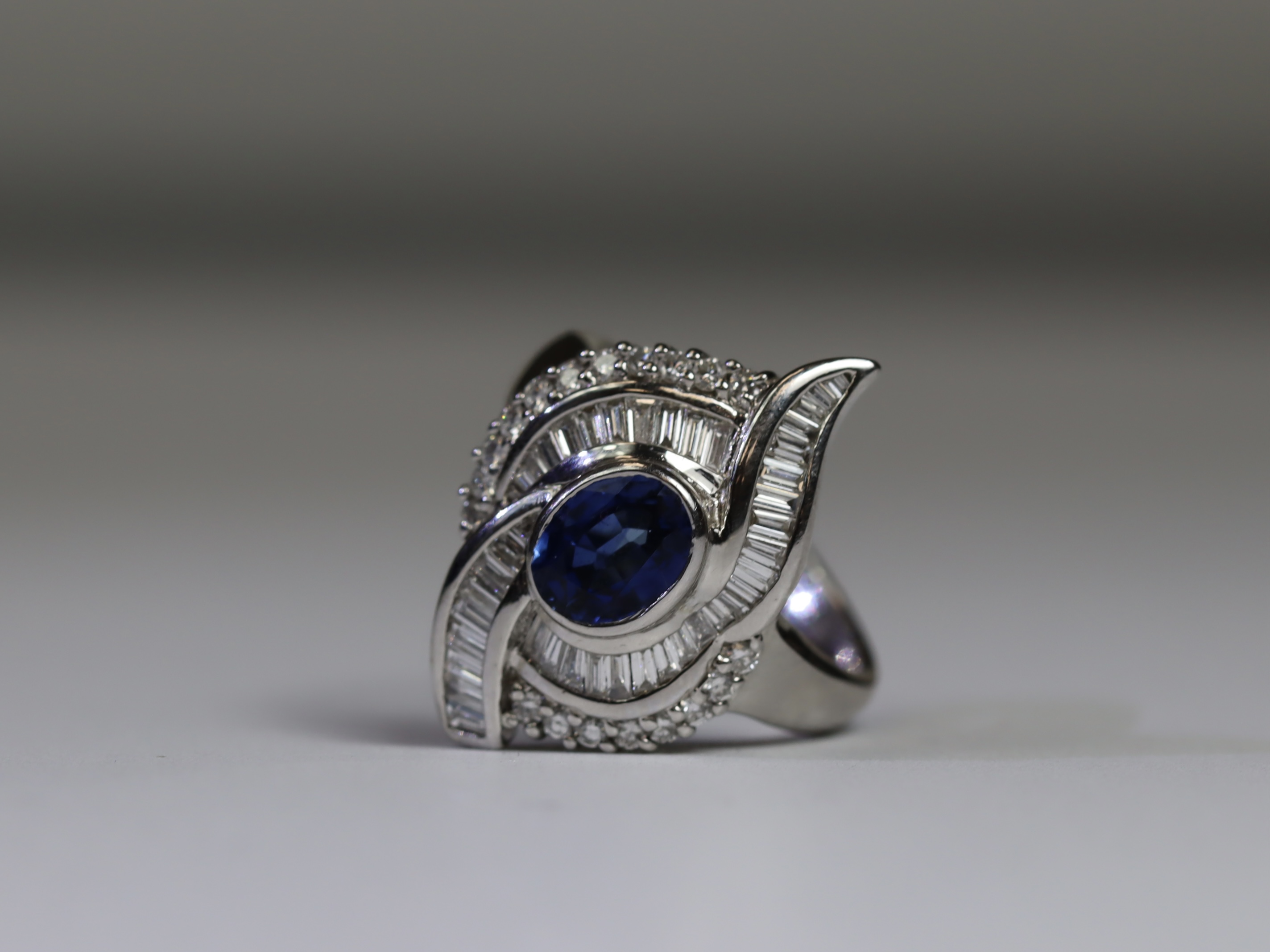 A contemporary Sapphire and Diamond Cluster Ring,the oval shaped central sapphire with rub over - Image 14 of 16