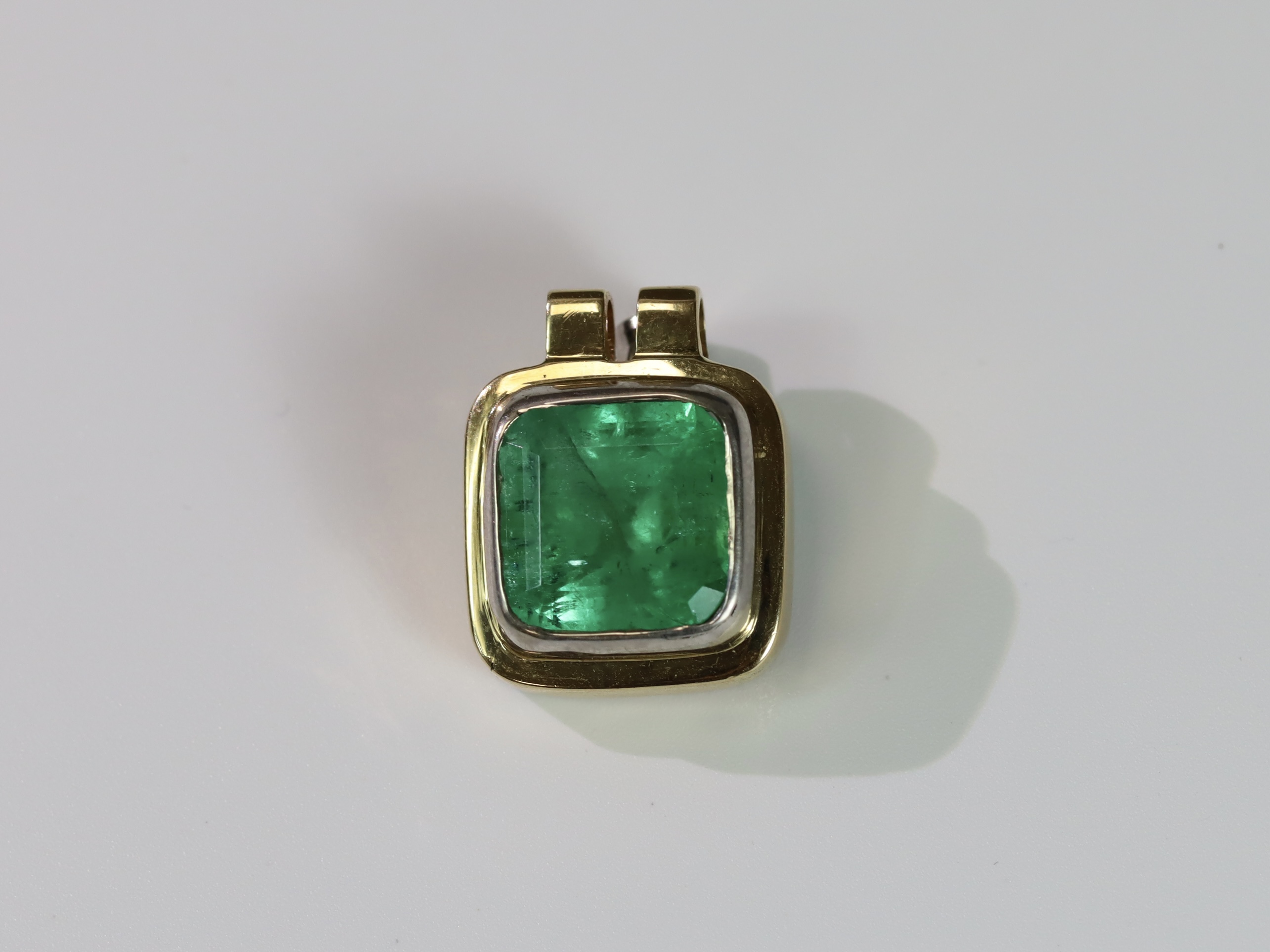 A Large Emerald Single Stone Pendant, the cushion shaped single stone emerald weighing approx. 12