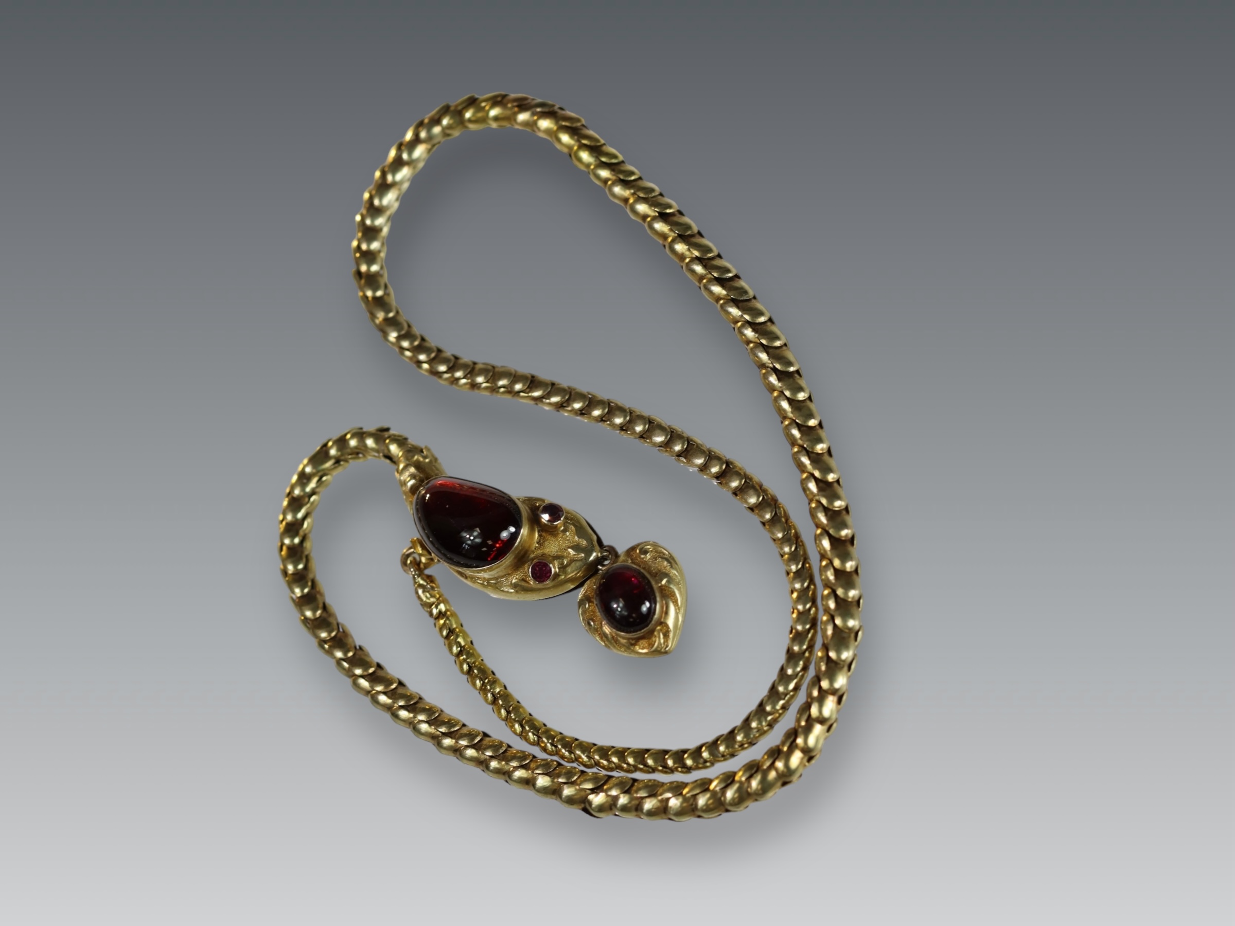 An attractive Antique Cabochon Garnet and Yellow Gold Snake Pendant, circa 1870,the head formed from