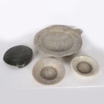 AN INDIAN CHAPATI STONE, A LARGE AND TWO SMALL CARVED STONE DISHES (4).