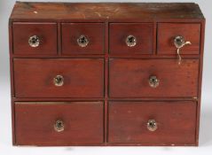 A DARK STAINED PINE BANK OF EIGHT APOTHECARY DRAWERS.