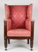 A REGENCY MAHOGANY AND UPHOLSTERED WING ARM CHAIR, UPHOLSTERED IN A RED FLORAL FABRIC.
