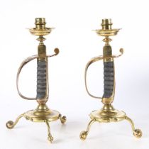 AN INTERESTING PAIR OF BRASS CANDLESTICKS MADE USING BRITISH ARMY SWORD HILTS AND SPURS, BY BENHAM &