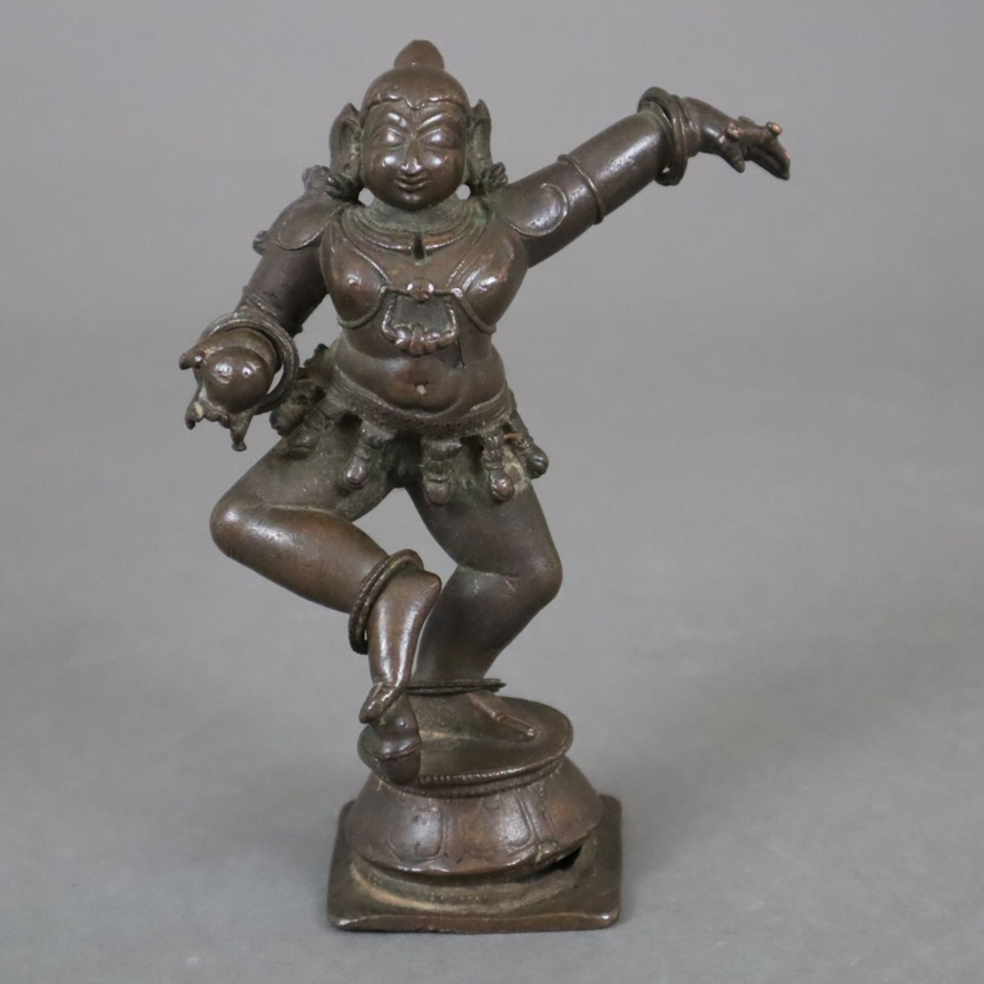 Tanzender Krishna mit der Butterkugel - Indien, Kupferlegierung, patiniert, Darstellung in Tanzhalt