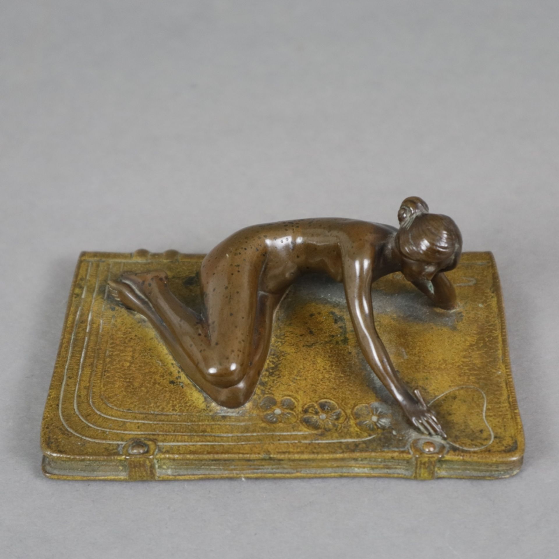 Jugendstil-Bronzeminiatur - um 1900, Frauenakt auf übergroßem ledergebundenem Notizheft ausgestreck