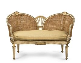 A Louis XVI-style cream painted and parcel gilt love seatEarly 20th centuryFirst seen in Season ...