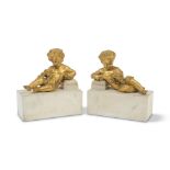 A pair of 19th century and later French gilt bronze and marble garniture figures of recumbent pu...