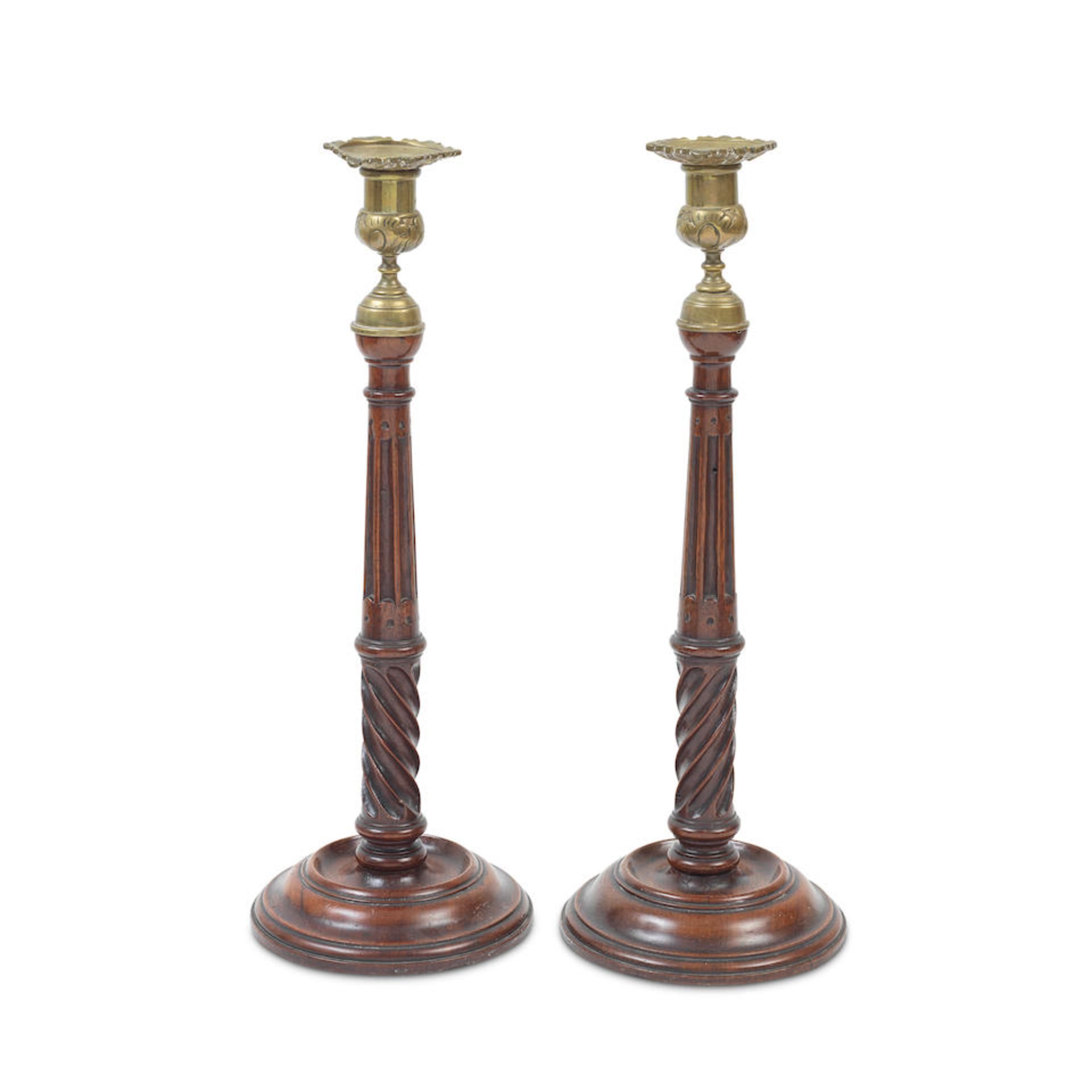 A pair of 19th century turned and carved mahogany and brass candlesticks In the George III style...