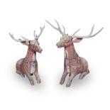 A pair of late 20th century far Eastern carved and red painted hardwood models of recumbent deer...