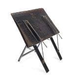 A Victorian black japanned, brass and tooled leather folio stand the edge of one board indisti...