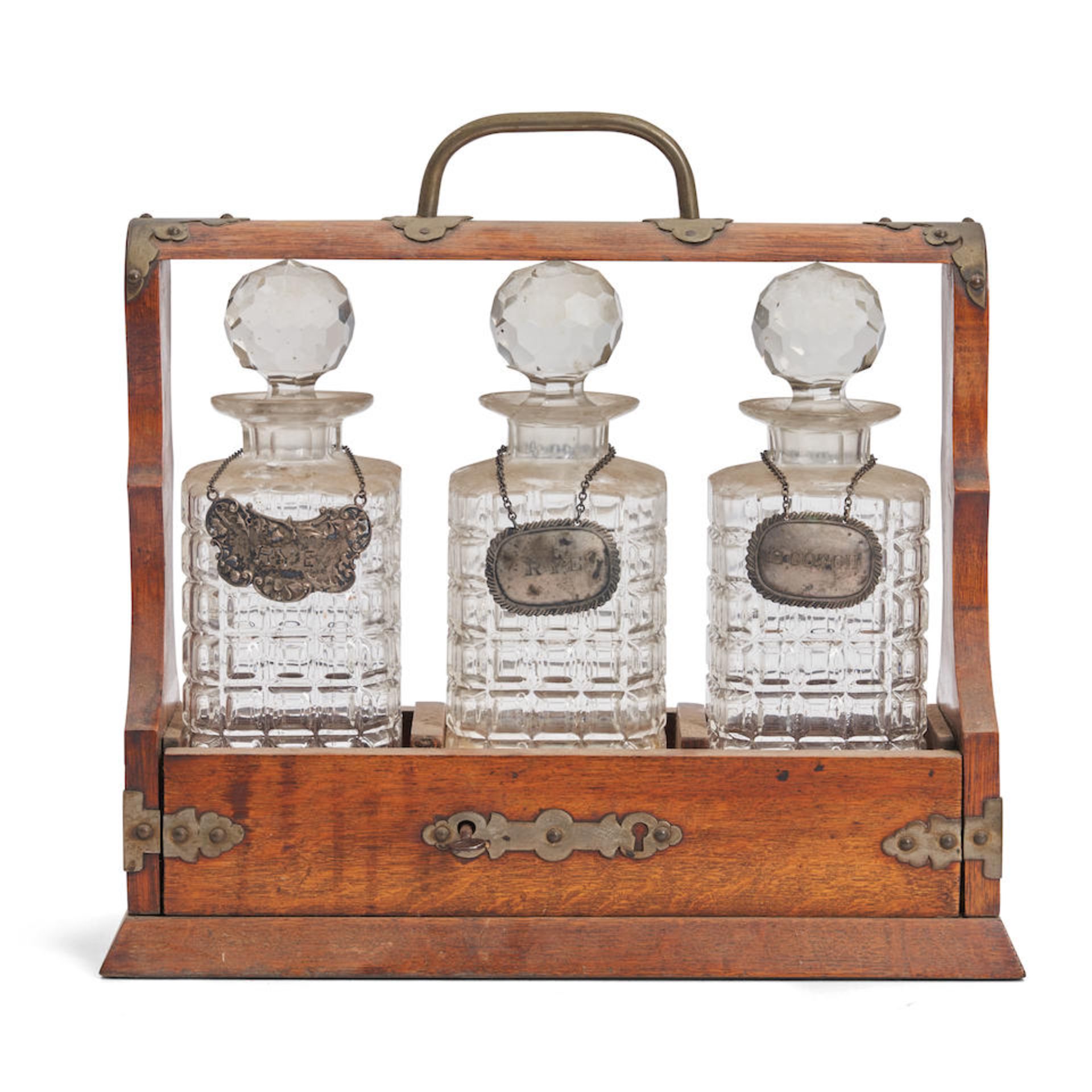 EDWARDIAN BRASS BOUND OAK TANTALUS WITH THREE PRESSED GLASS BOTTLES/DECANTERS