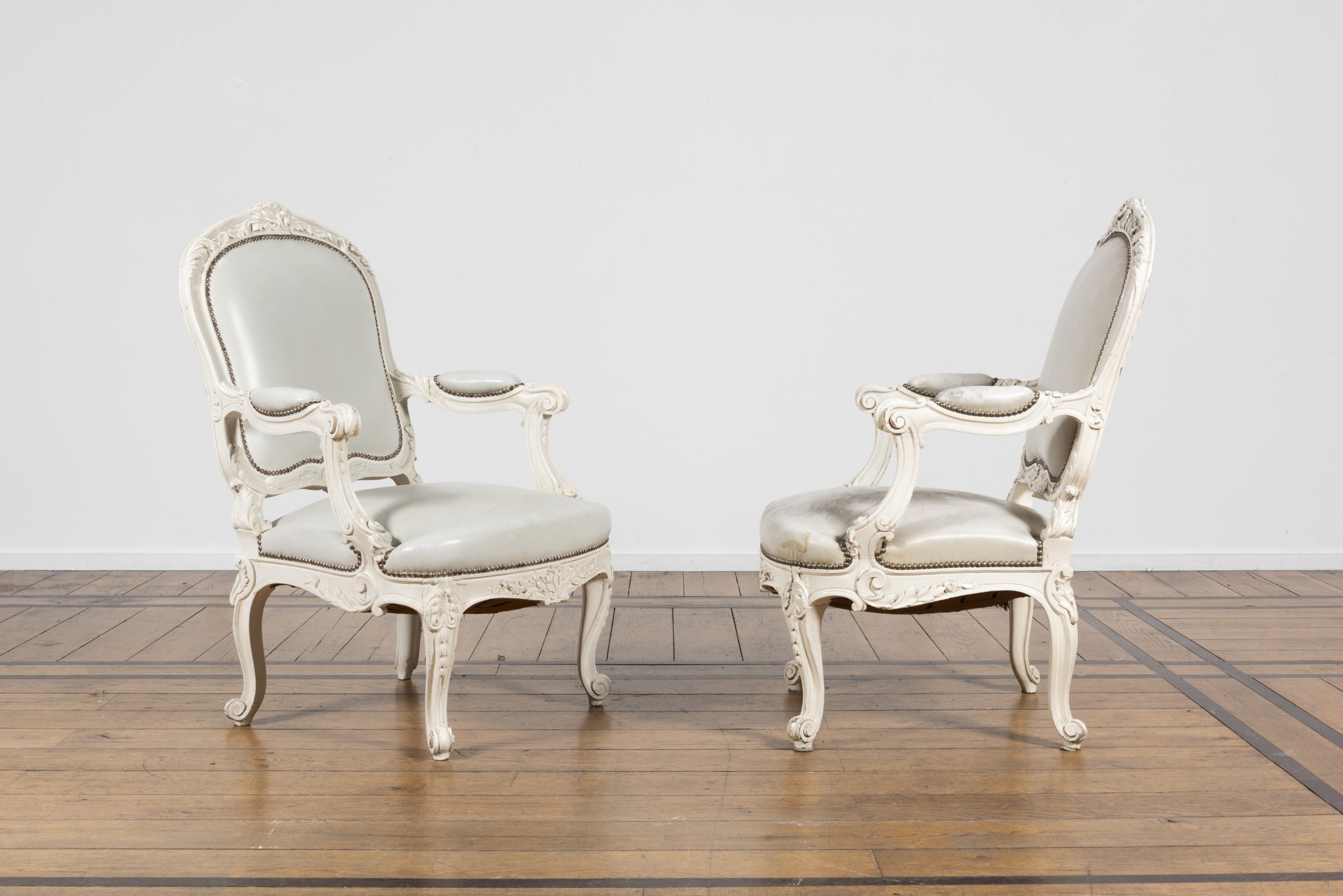 Paire de fauteuils en bois peint et assise en cuir. Style Louis XV