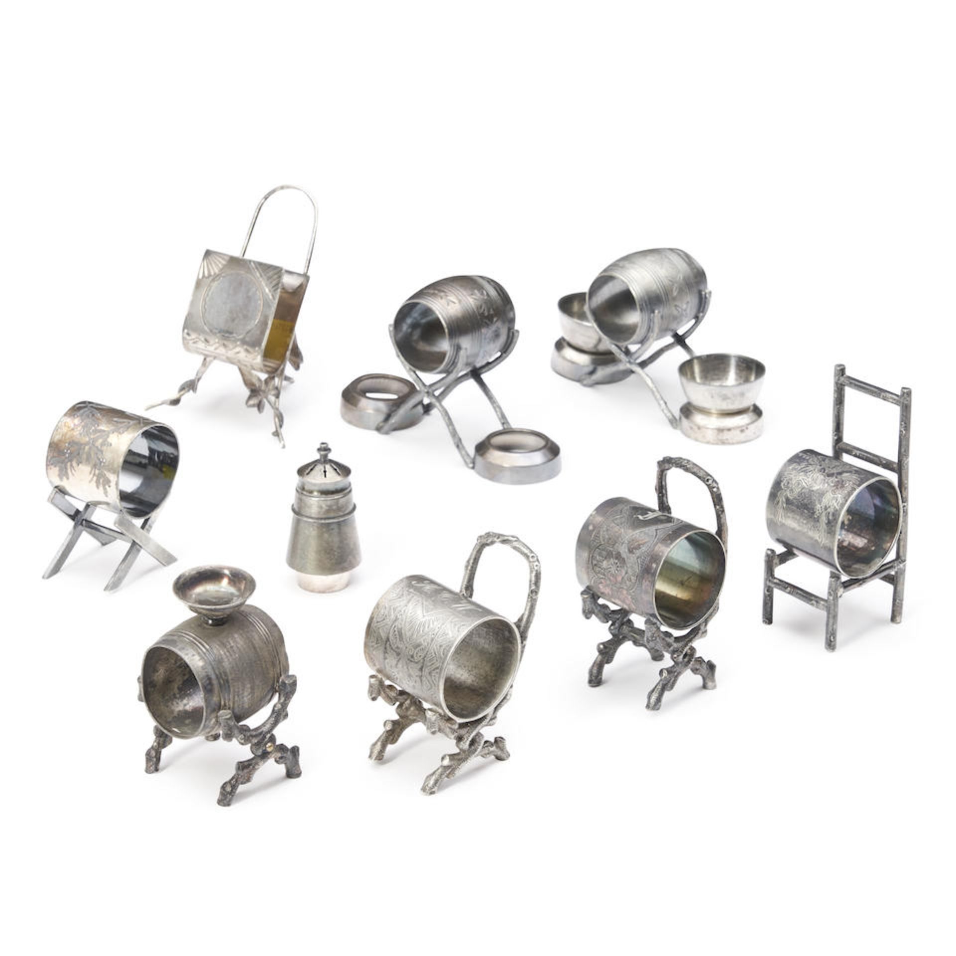 EIGHT SILVER-PLATED NAPKIN RINGS ON CHAIRS AND STOOLS