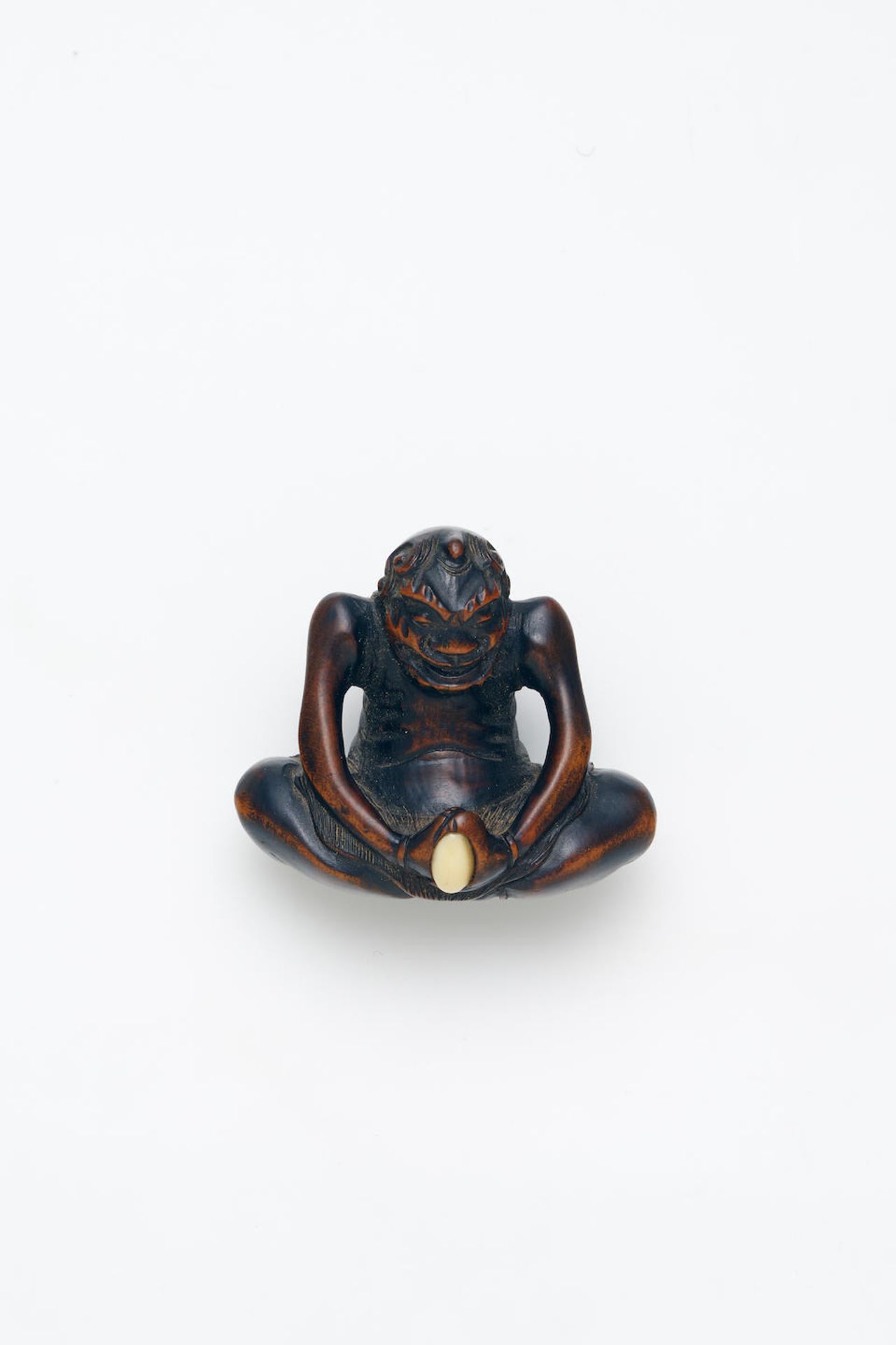 A SHELL-INLAID WOOD NETSUKE OF AN ONI Edo Period, 19th Century