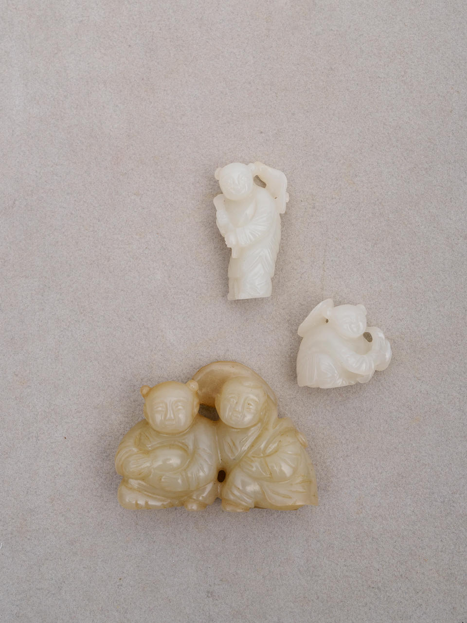 Three white and celadon jade 'child' toggles 19th/ 20th century (3)