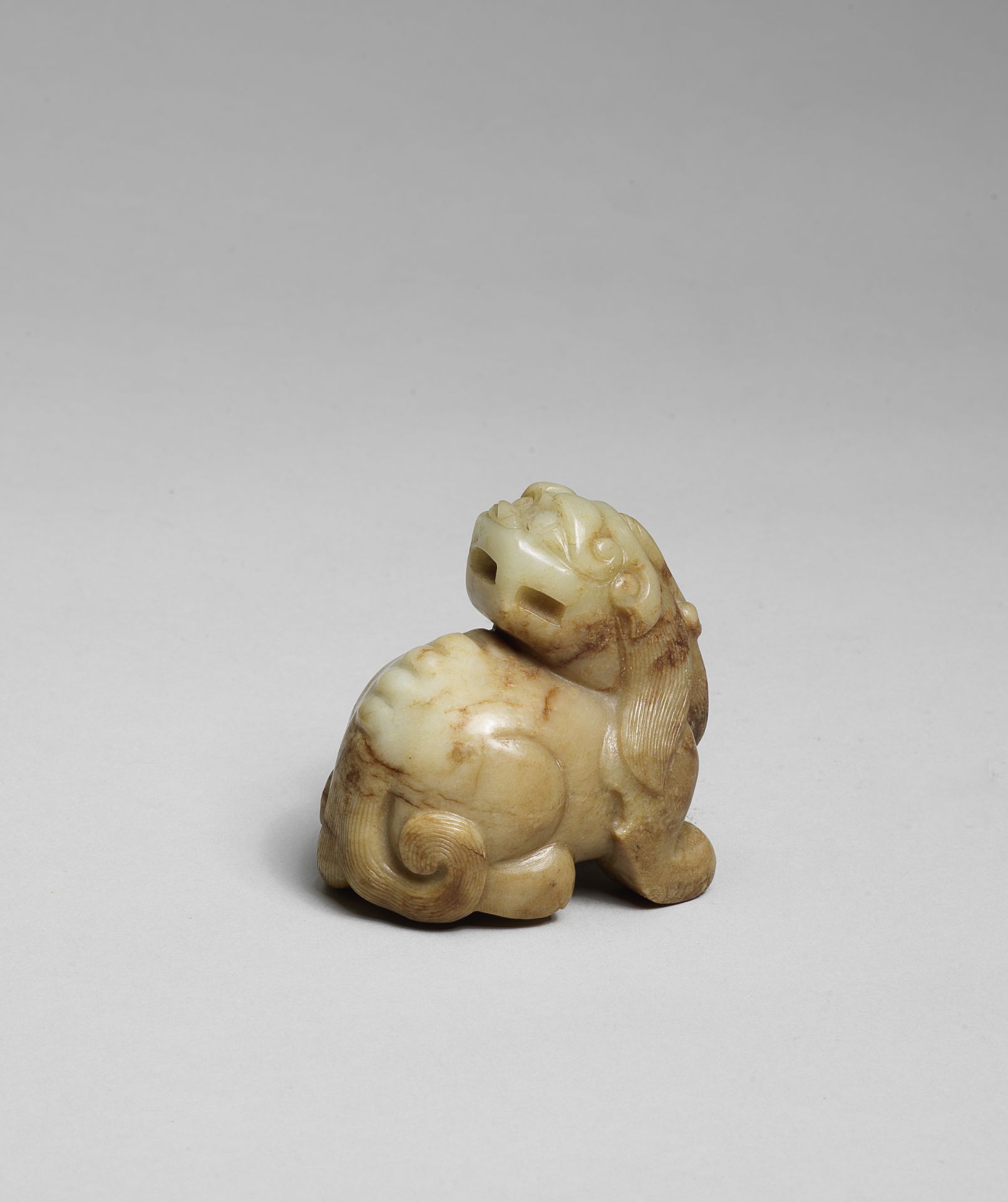 A PALE GREEN AND RUSSET JADE CARVING OF A MYTHICAL BEAST Ming Dynasty