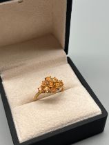 10ct yellow gold ring set with orange gem stones and fitted with eight small round cut diamonds. [