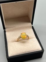 10ct yellow gold ring set with an Ethiopian opal cabochon stone flanked by green spinel stones. [