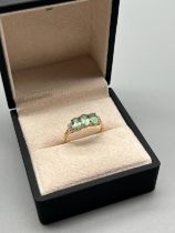 10ct yellow gold ring set with three oval cut green topaz stones flanked by white round cut spinel