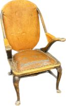 Antique reclined chair, the shaped back over open arms and a cushioned seat, the whole covered in