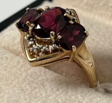 9ct yellow gold ring set with three oval cut purple Garnet stones flanked by round cut diamonds. [