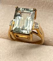 9ct yellow gold ring set with a large emerald cut aquamarine gem stone off set by diamond shoulders.