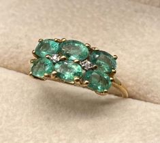 10ct yellow gold ring set with six oval cut emerald gem stones and two round cut diamonds. [Ring