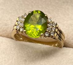 9ct yellow gold ring set with an oval cut green gem stone off set by two rows of round cut