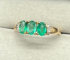 10ct yellow gold ring set with three oval emerald gem stones off set by baguette cut diamond