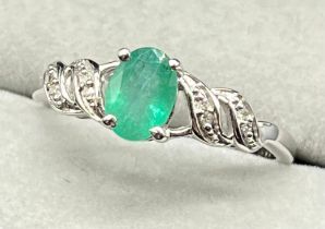 10ct white gold ring set with an oval cut emerald stone with diamond shoulders. [Ring size Q] [2.