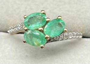 10ct yellow gold ring set with three oval cut emerald stones and round cut white topaz stones. [Ring