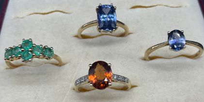Four 10ct yellow gold rings; Fitted with various gem stones- Emerald, Orange Garnet and Iolite. [9.