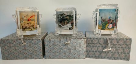 A collection of three oriental reverse painted glass preserve jars with covers and silk fitted boxes