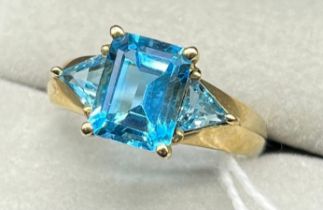 9ct yellow gold ring set with a Emerald cut blue topaz and two triangle cut blue topaz stones. [Ring