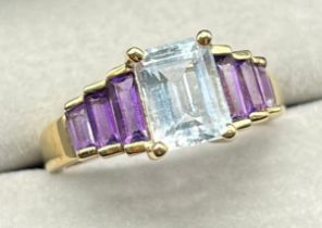 9ct yellow gold ring set with an emerald cut blue aquamarine stone of set by three baguette cut