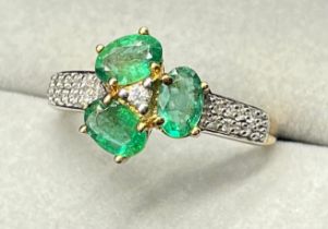10ct yellow gold ring set with three oval cut emerald gem stones surrounded by round cut white topaz