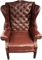 Ox blood leather button back Churchill chesterfield high back wing chair with brass nail head trim.