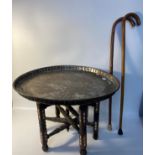 Eastern topped brass table with wooden supports together with two walking sticks