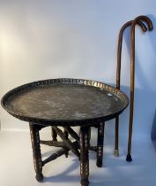 Eastern topped brass table with wooden supports together with two walking sticks