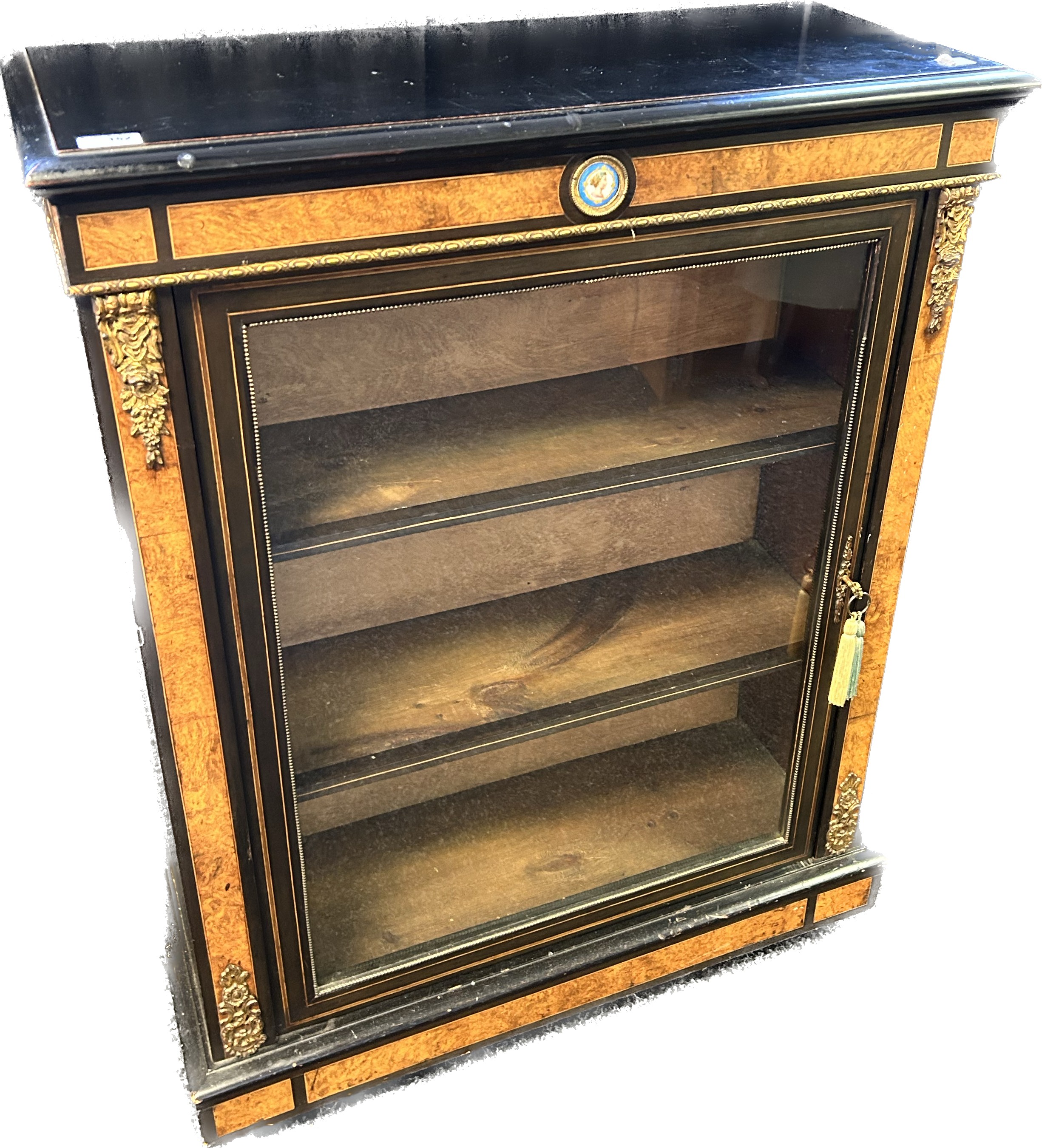 Reproduction blackened display unit with walnut veneer, the glazed door opening to shelved interior,