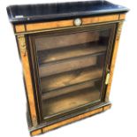 Reproduction blackened display unit with walnut veneer, the glazed door opening to shelved interior,