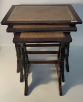 Nest of three reproduction leather topped tables, raised on trestle legs
