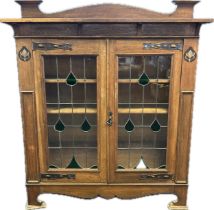 Arts and crafts bookcase, the back rail above two stained glass glazed doors opening to
