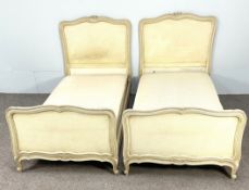 A pair of vintage French Louis XVI style single bedsteads, with moulded and craquelure cream painted