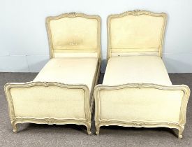 A pair of vintage French Louis XVI style single bedsteads, with moulded and craquelure cream painted