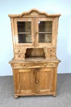 A vintage Continental style pine side cabinet, 20th century, with an arched top, over a glazed two