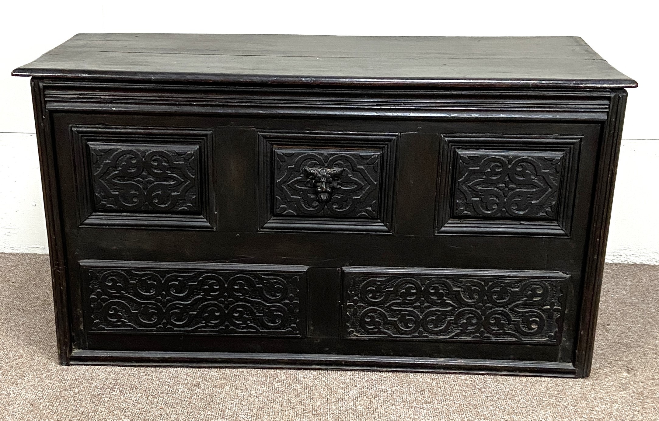 A Carolean oak coffer, 17th century and later, the front carved with moulded and divided panels,