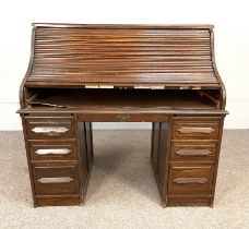 An Edwardian oak tambour front desk, with a variety of pigeon holes and niches over a writing
