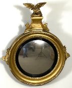 A Regency gilt convex wall mirror, with eagle surmount, circular beaded frame, the edges set with